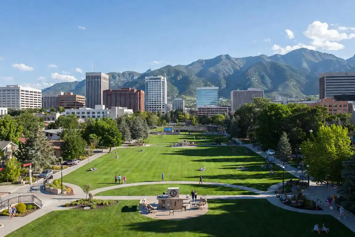 Wide green lawn at Fairmont Park in Salt Lake City, Utah, with city buildings and mountains in the background.