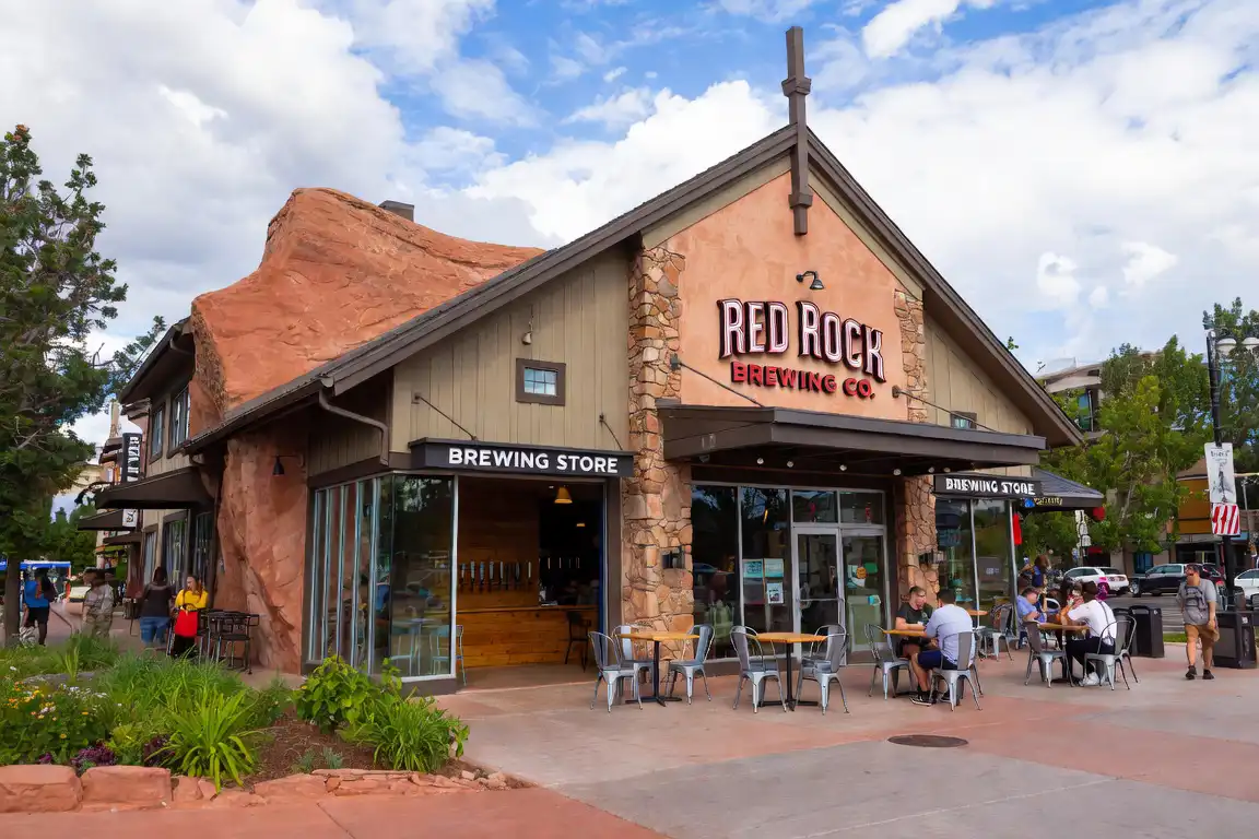 Exterior of Red Rock Brewing Beer Store in Salt Lake City, Utah, with outdoor seating and stone architectural details.
